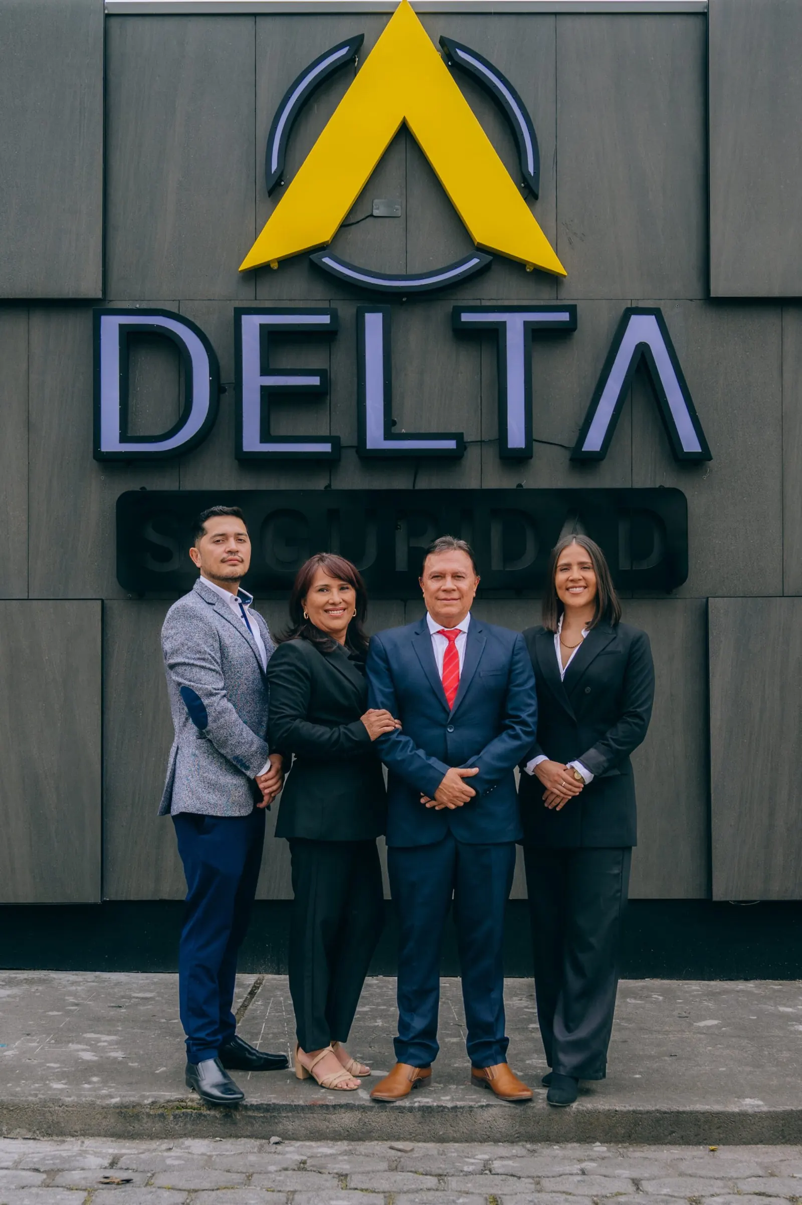 Directivos de Delta Seguridad junto al logotipo de la empresa